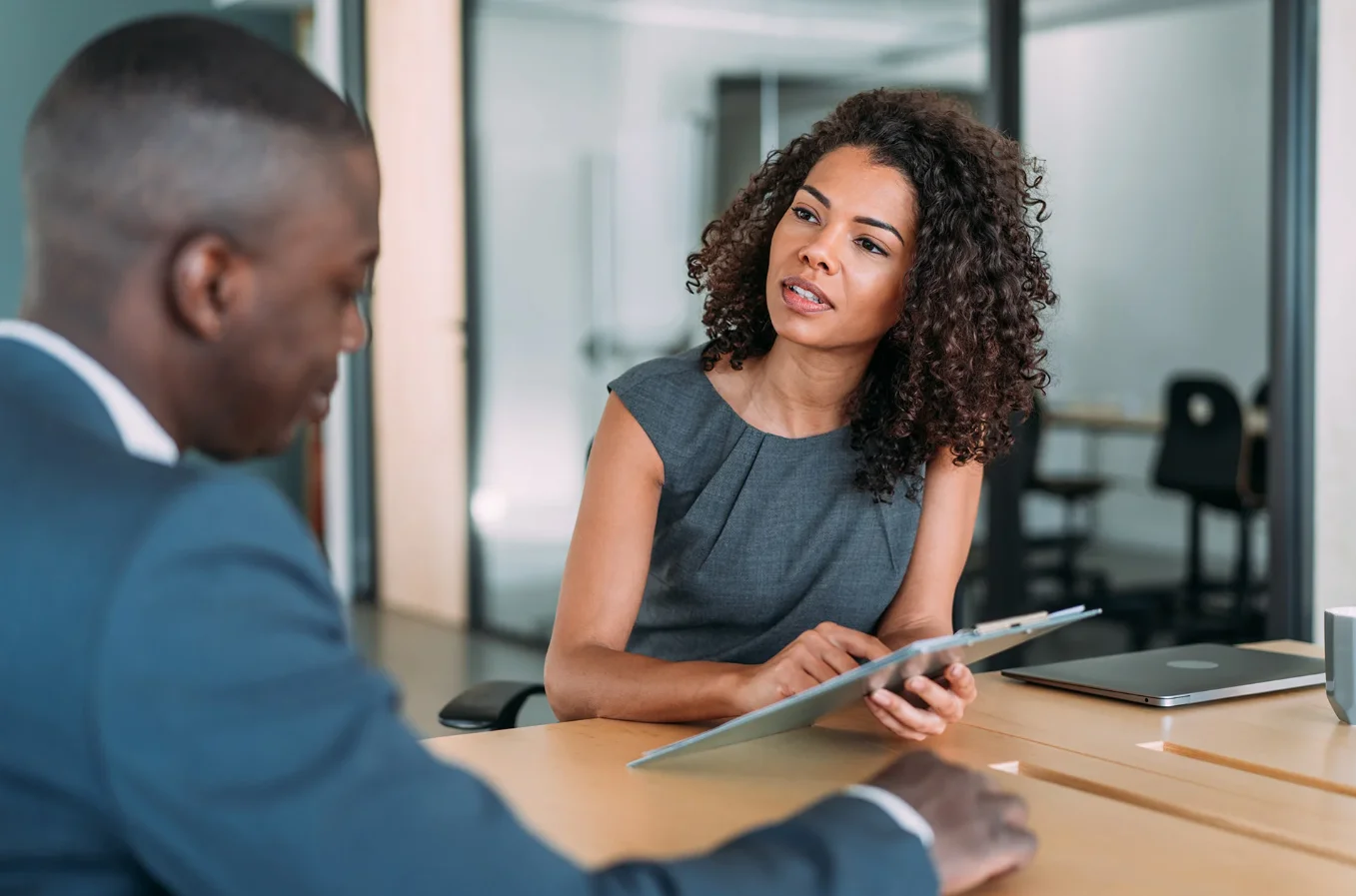 Foto: Ein Mann und eine Frau im Business-Look unterhalten sich in einem Besprechungsraum.