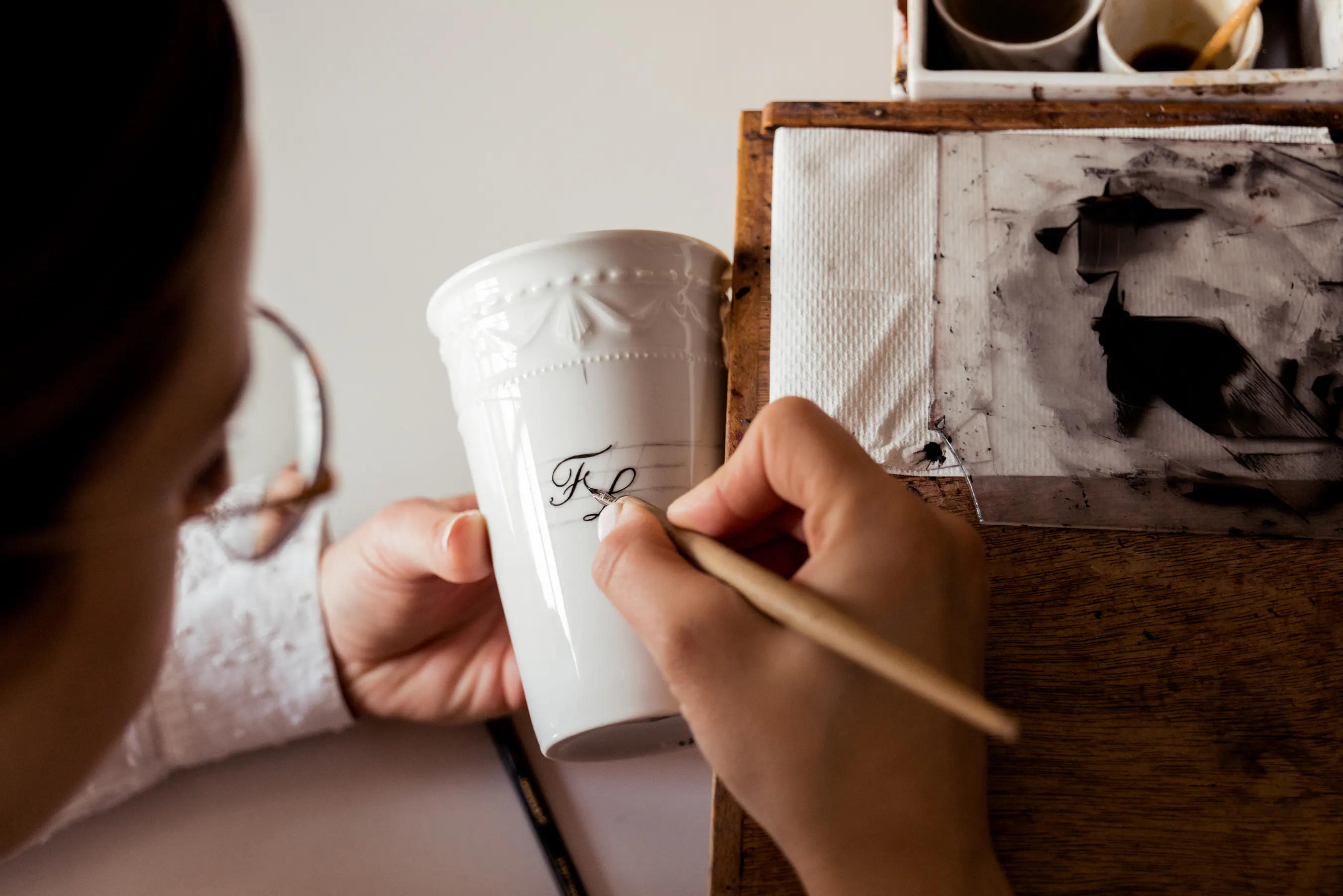 Königliche Porzellan-Manufaktur Berlin (KPM) - Mitarbeiterin bei der Arbeit Mitarbeiterin der KPM bemalt händisch eine Porzellan-Tasse