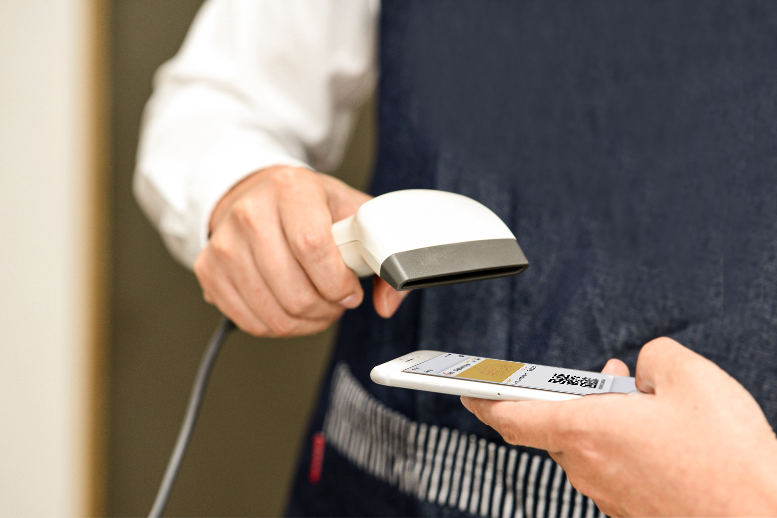 Foto: Ein Mann scannt einen QR-Code vom Smartphone eines Gasts.
