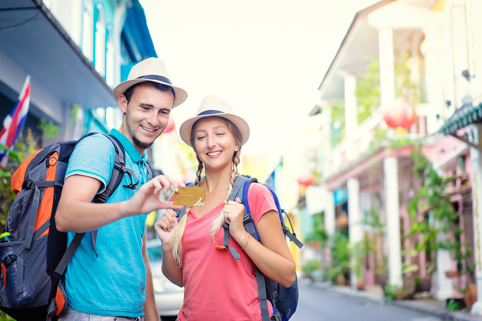Foto: Ein junges Paar mit Strohhüten und Rucksäcken steht auf der Straße und begutachtet die AVS Tourist-Card. 